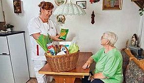 Das Bild zeigt eine Hauswirtschaftskraft, die den Einkauf für eine Patienten aus einem Einkaufskorb auspackt