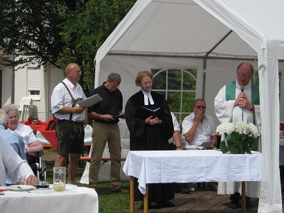 Das Bild zeigt zwei Pfarrer und mehrere Männer vom Chor